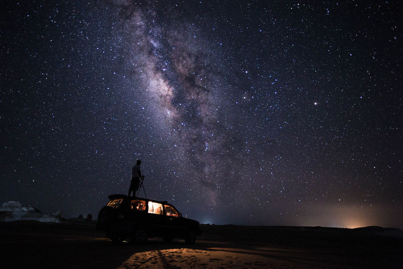 银河系下的人在车辆顶部的轮廓