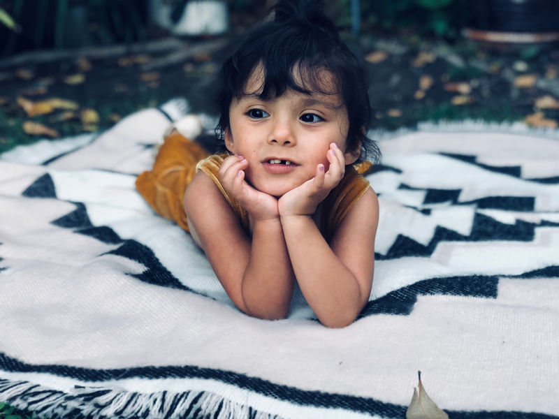 女孩手放在下巴下面躺在白色的垫子上