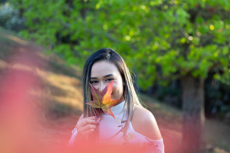 女人穿着冷肩上衣抱着树叶微笑