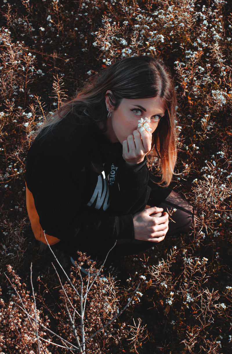 拿着白色花瓣的女人坐在花场上