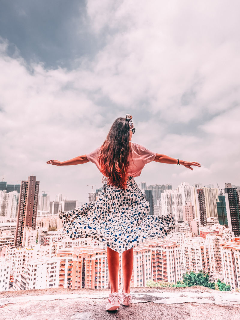 白天在建筑物前张开双臂的女人