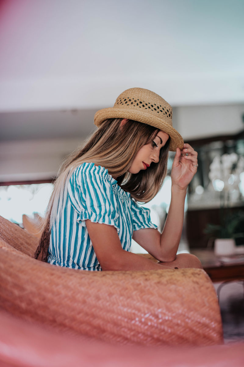 坐在沙发椅上碰帽子的女人