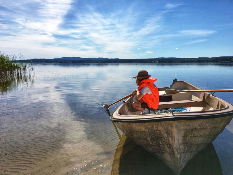 坐在棕色独木舟上的人在白云和蓝天下