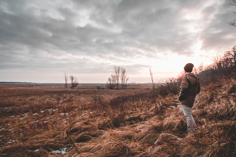 站在灰色天空下褐色草地上的人