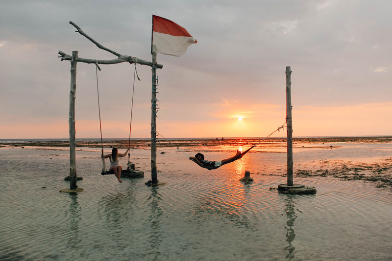 两个人在靠近水体的秋千上