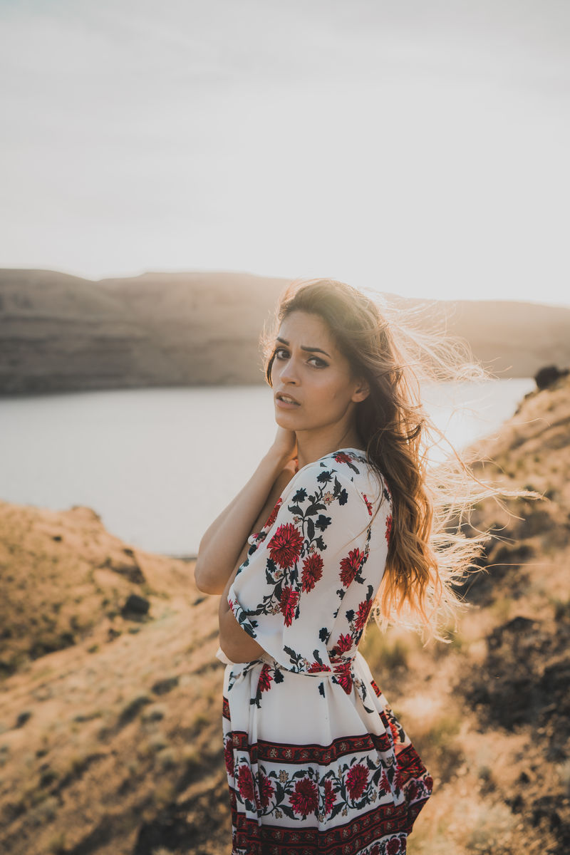 站在靠近水体的褐色山丘上的女人