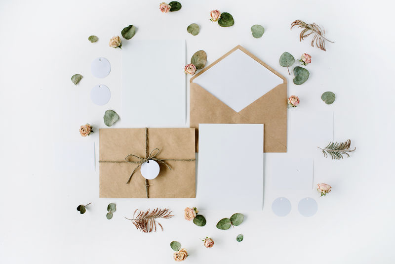 平铺工作区-婚礼请柬、工艺信封、白底粉红玫瑰和绿叶-顶视图-顶视图