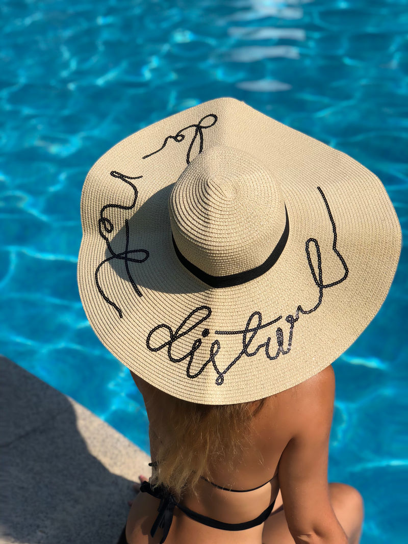 坐在池边的女人戴着太阳帽