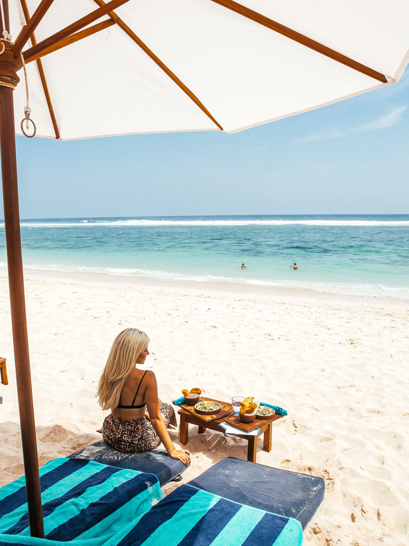 坐在海边阳伞下的女人