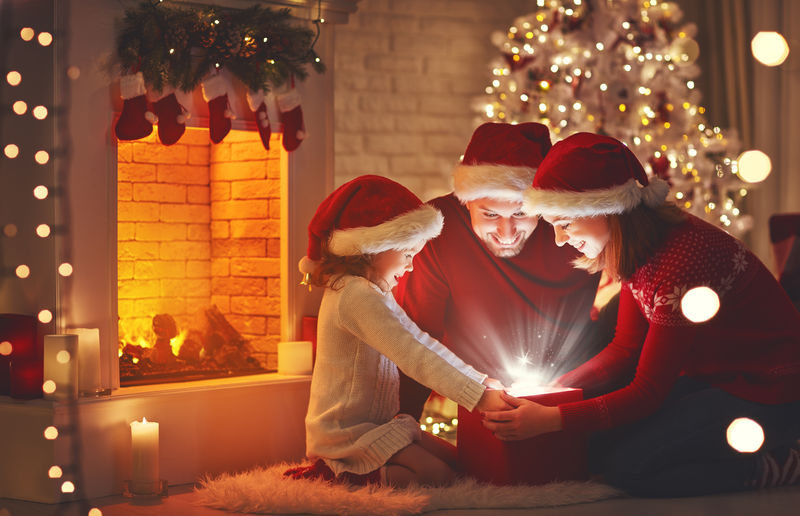 圣诞快乐！幸福的家庭-母亲-父亲和孩子-带着魔法礼物在树旁