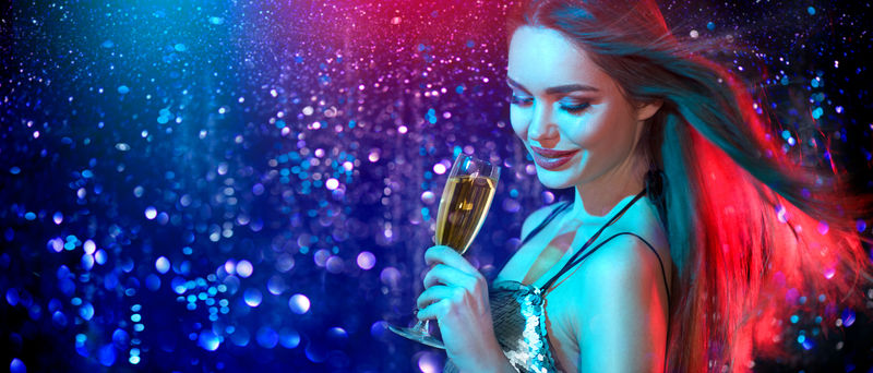 在迪斯科舞会上喝着香槟、跳舞的模特儿-在假日里红底蓝底-美女-完美的时尚妆容-圣诞节和新年庆祝活动