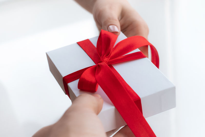礼品盒与一个红色丝带蝴蝶结隔离在一个明亮的白色背景。亲手为情人节送礼物。爱与假日的概念。