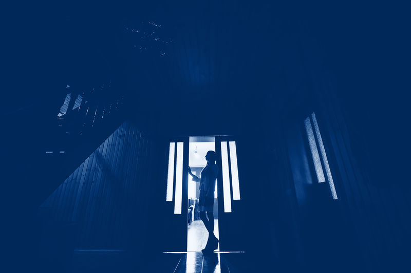 经典的蓝色调剪影的女孩在门口的房子。时尚2020年色彩