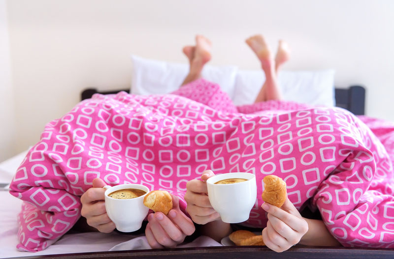 快乐的年轻夫妇在床上吃早餐。