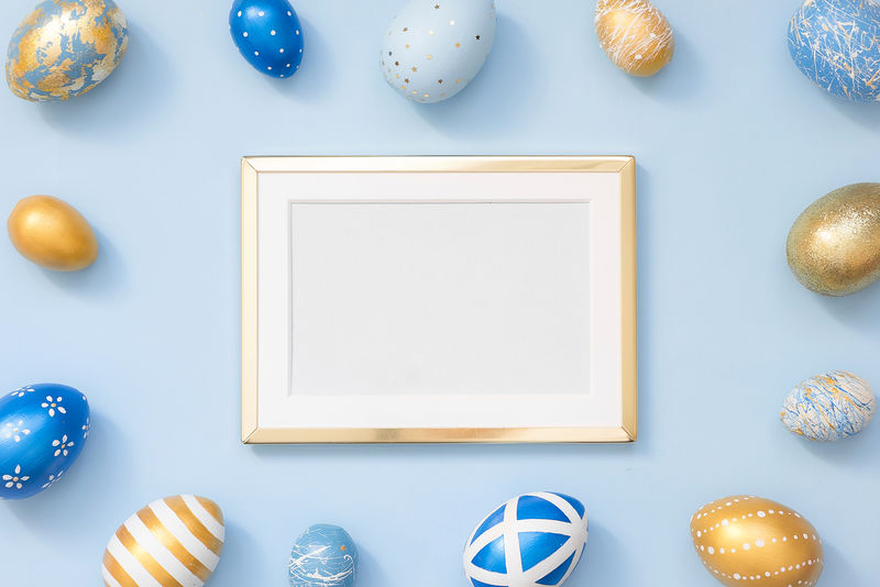 框架用金色装饰的复活节彩蛋,蓝色背景上有文本复制空间。最小的复活节快乐概念。俯视图,平面图。