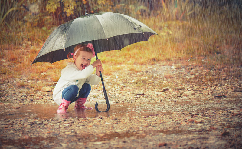 快乐的小女孩带着雨伞在自然中嬉戏