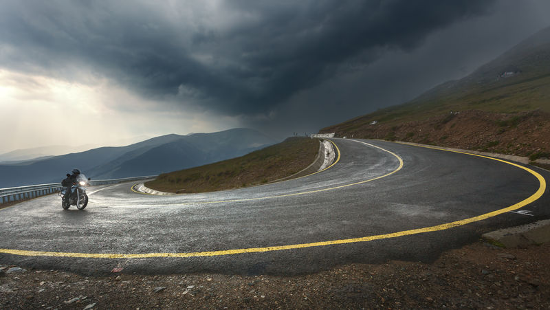 驾驶摩托车在阿尔卑斯公路上冲向暴风雨