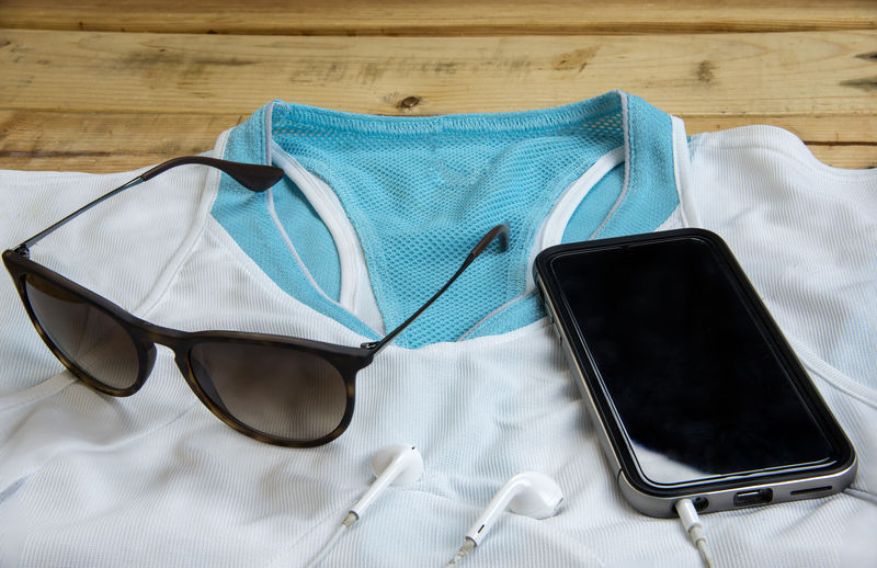 木质背景的运动服、眼镜和智能手机