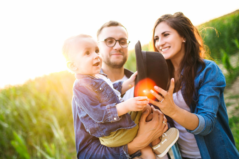 年轻时髦的爸爸妈妈抱着可爱的孩子在玉米地里