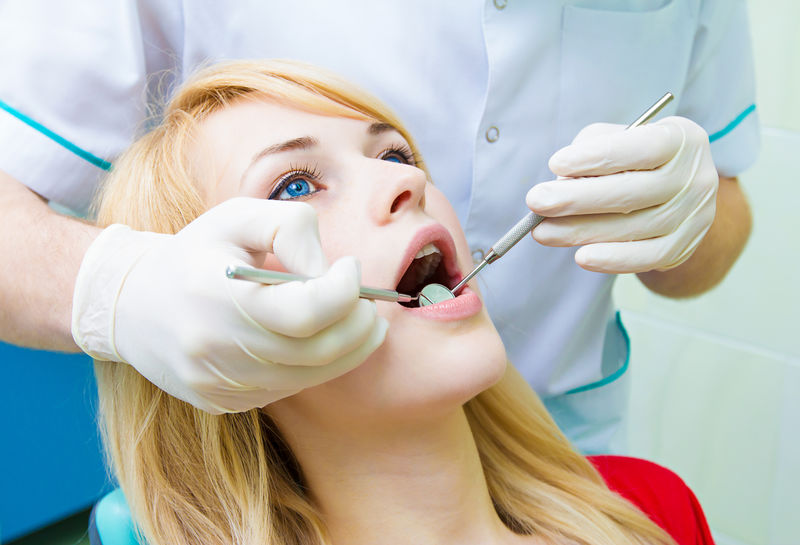 牙医检查年轻成人病人，清洁牙齿