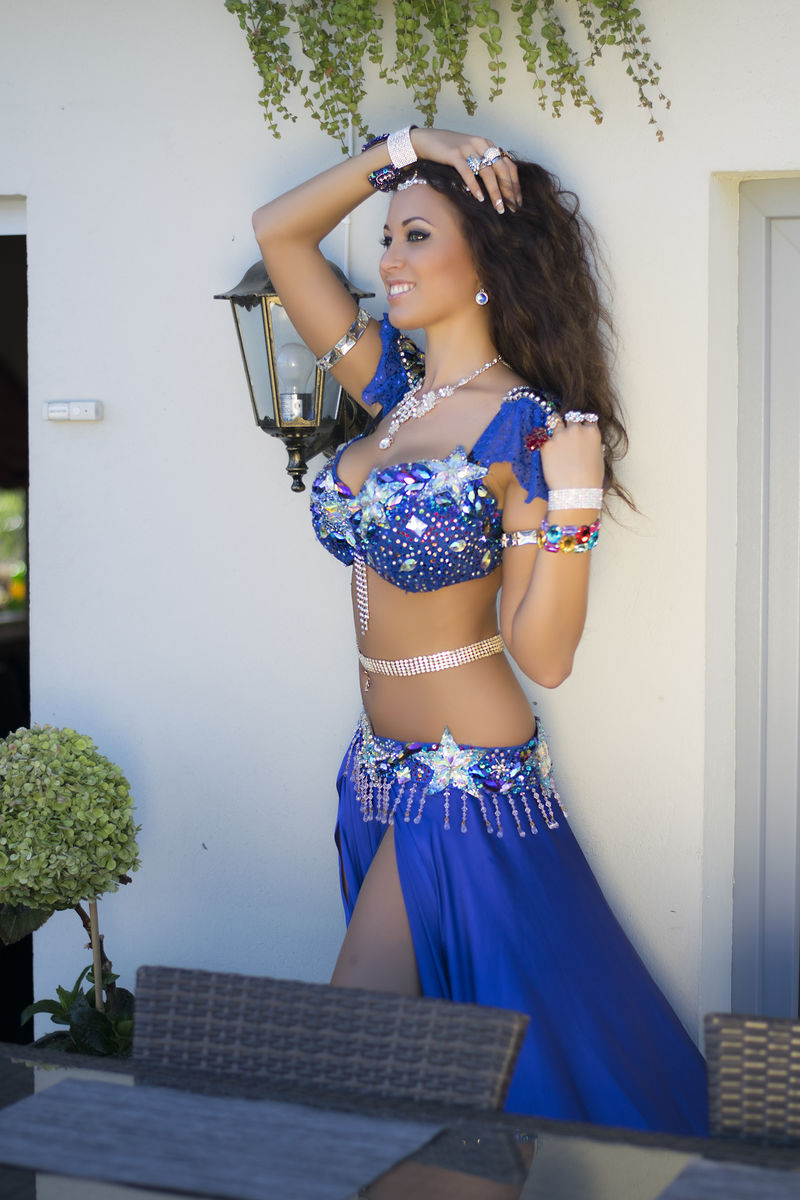 穿着蓝色服装的肚皮舞女微笑着，阳光明媚的夏日