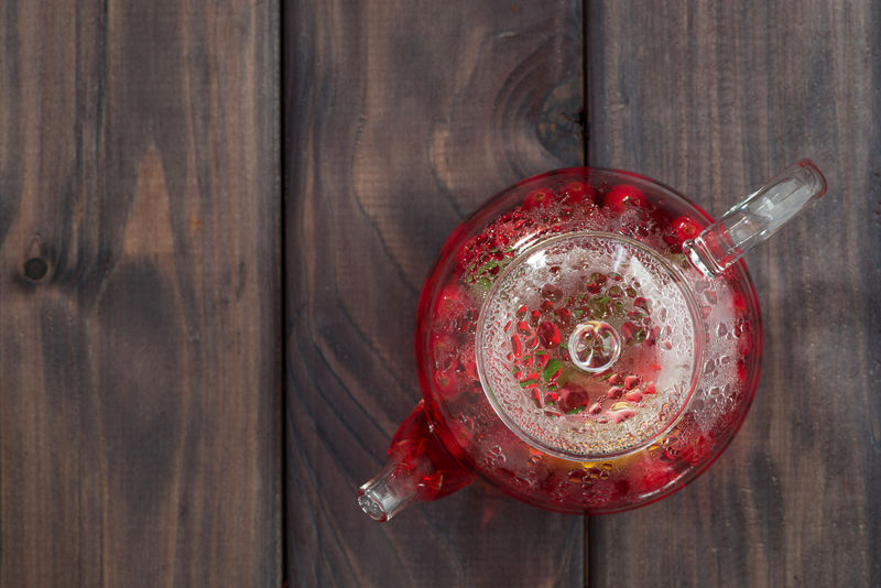 黑木桌上的玻璃茶壶里的浆果茶