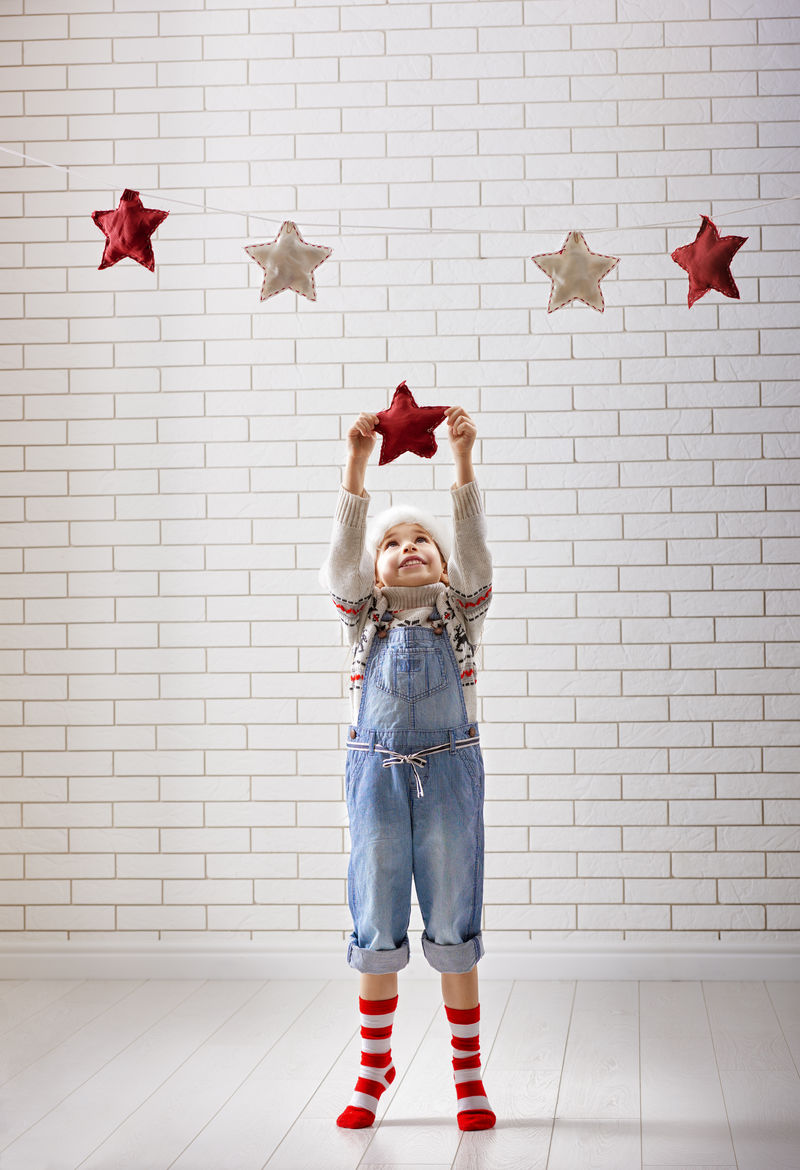 平安夜！一个小孩把星星挂在花环上。