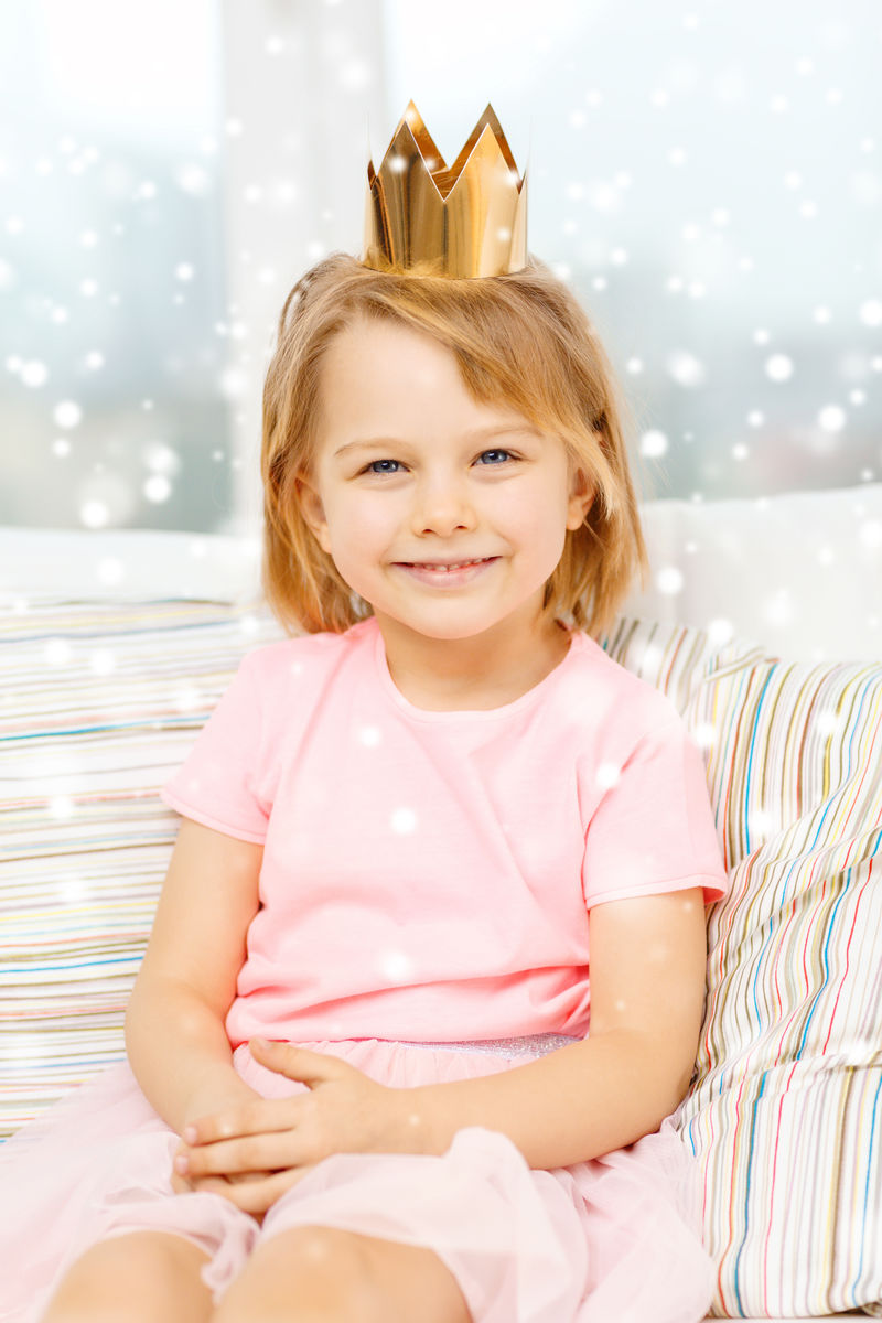 坐在沙发上微笑的皇冠小女孩