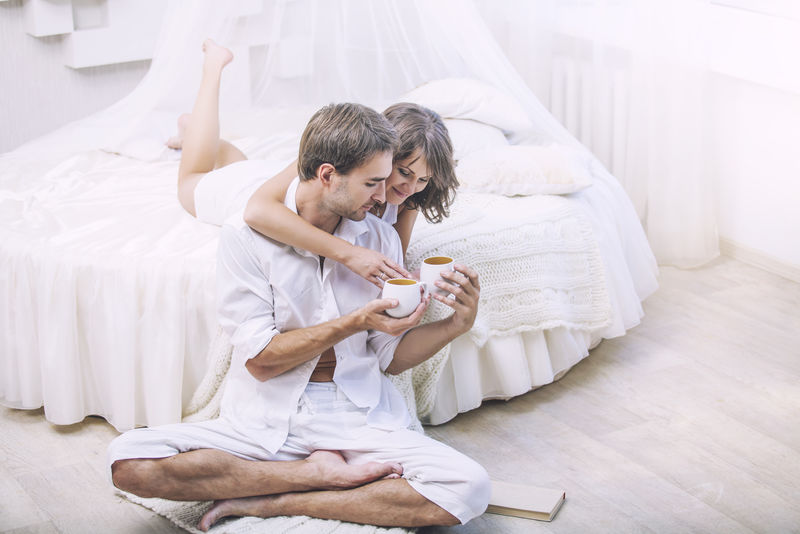 夫妻俩在家里躺在床上喝杯咖啡
