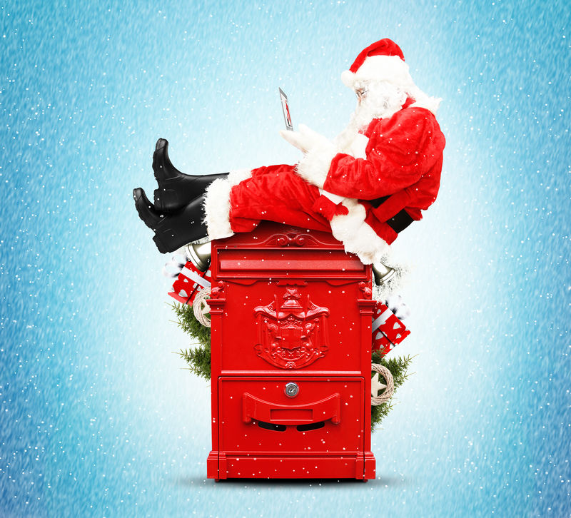 圣诞老人拿着笔记本电脑坐在邮箱里