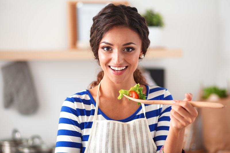 年轻女子在现代厨房吃新鲜沙拉