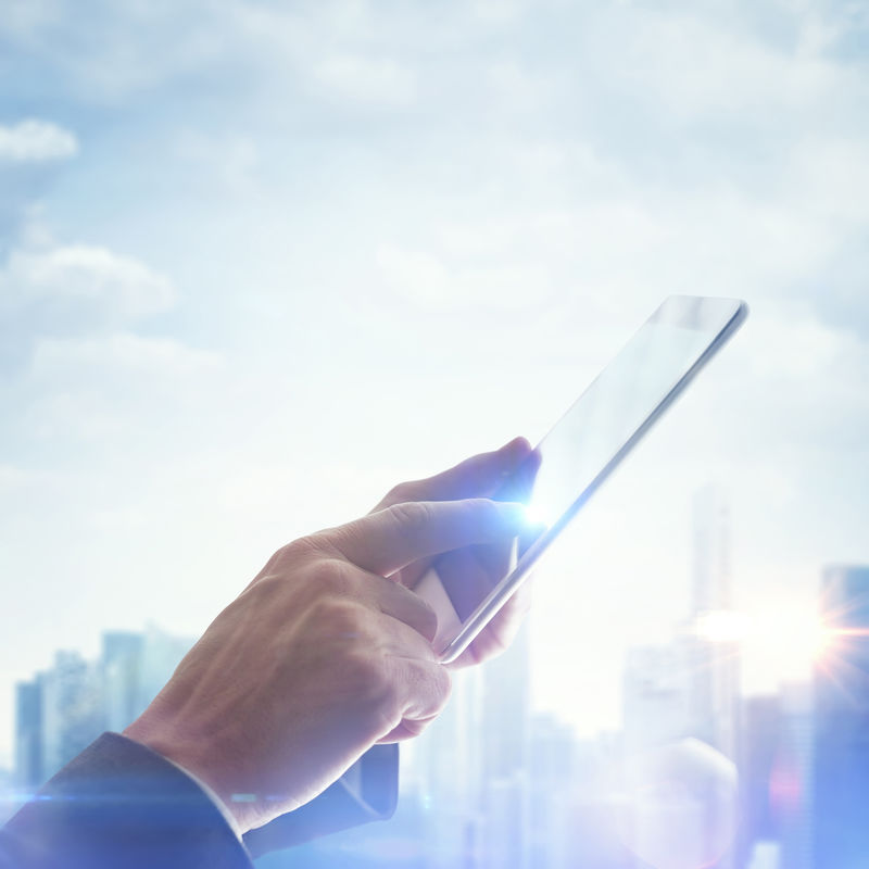 在模糊的马加罗波利斯背景上手持数字平板电脑