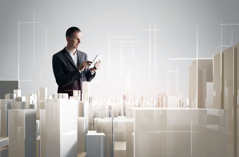 拥有平板电脑的商人与一个现代城市项目合作