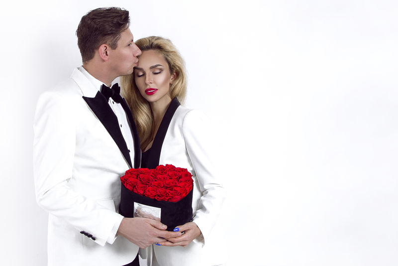 幸福美丽的情侣摆在白色背景上，手持红心花盒。情人节，婚礼-图片
