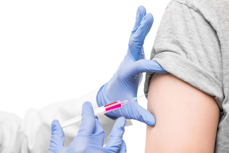戴白衣的护士戴着手套的手拿着抗covid19疫苗的注射器