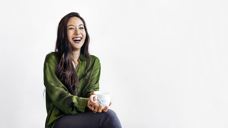 坐在白墙旁的美丽欢快的女人