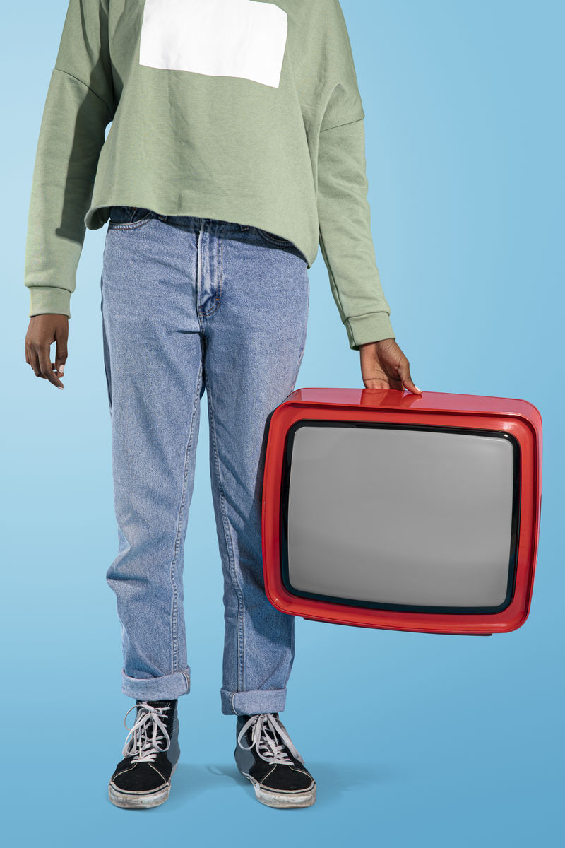 拿着一台旧的红色电视机的女人