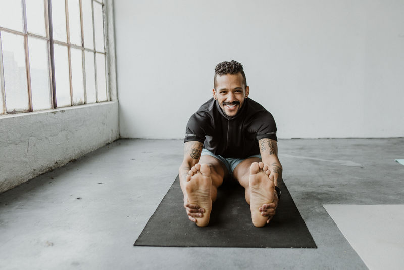 快乐的男人在瑜伽垫上伸展身体