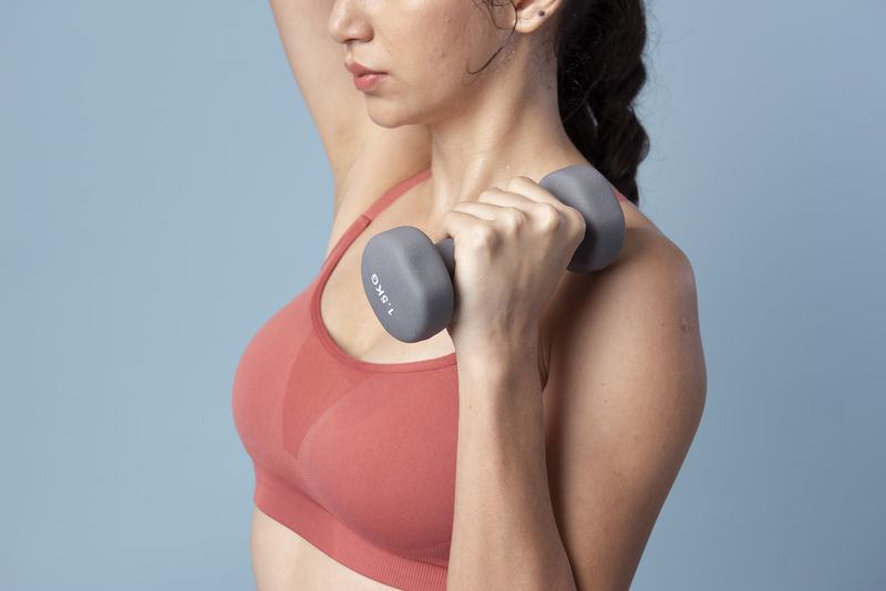 运动型女子举哑铃在蓝色背景