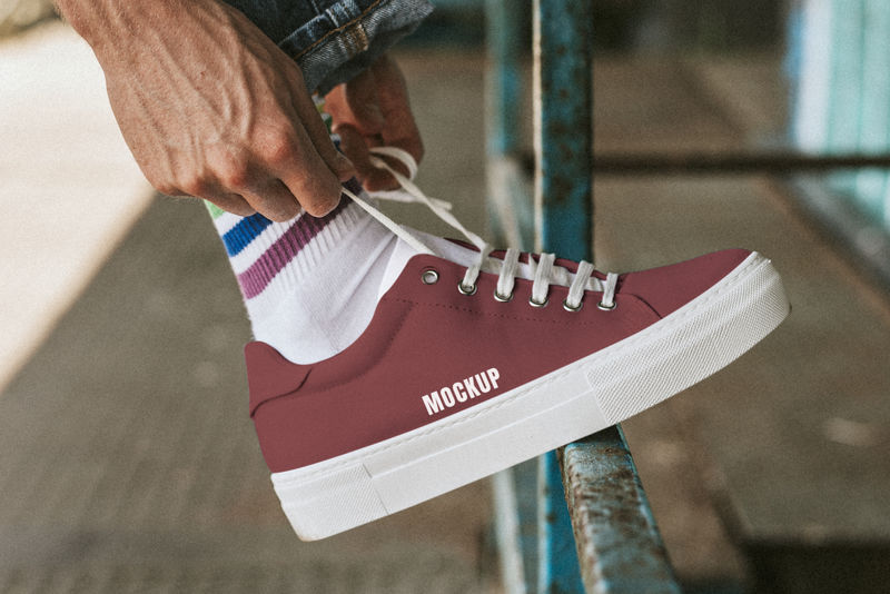 在红色运动鞋模型上固定鞋带的人