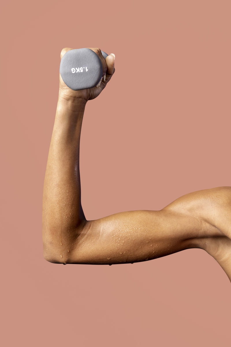 手举橙色背景上的哑铃