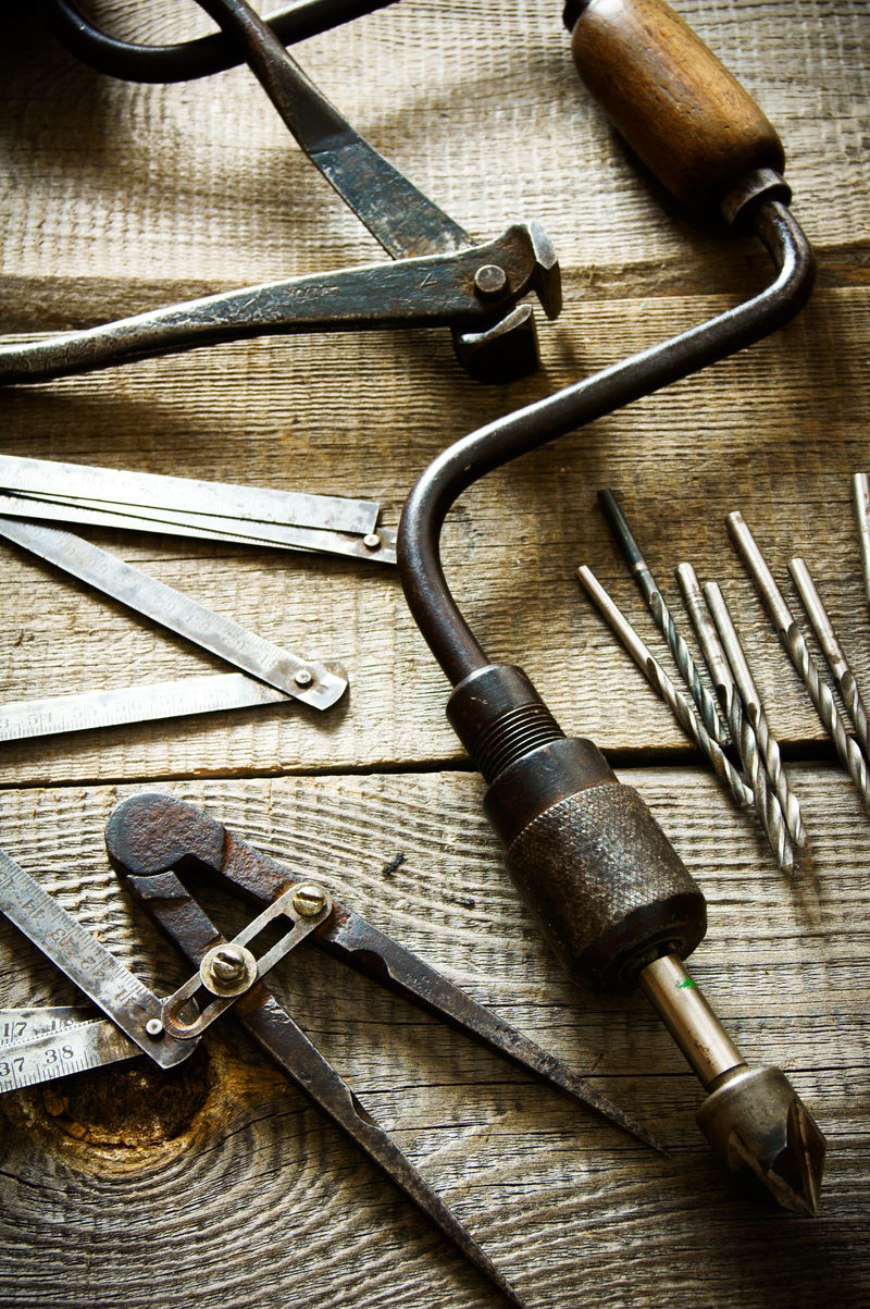 木制背景上的旧钻圆规尺子和钻头