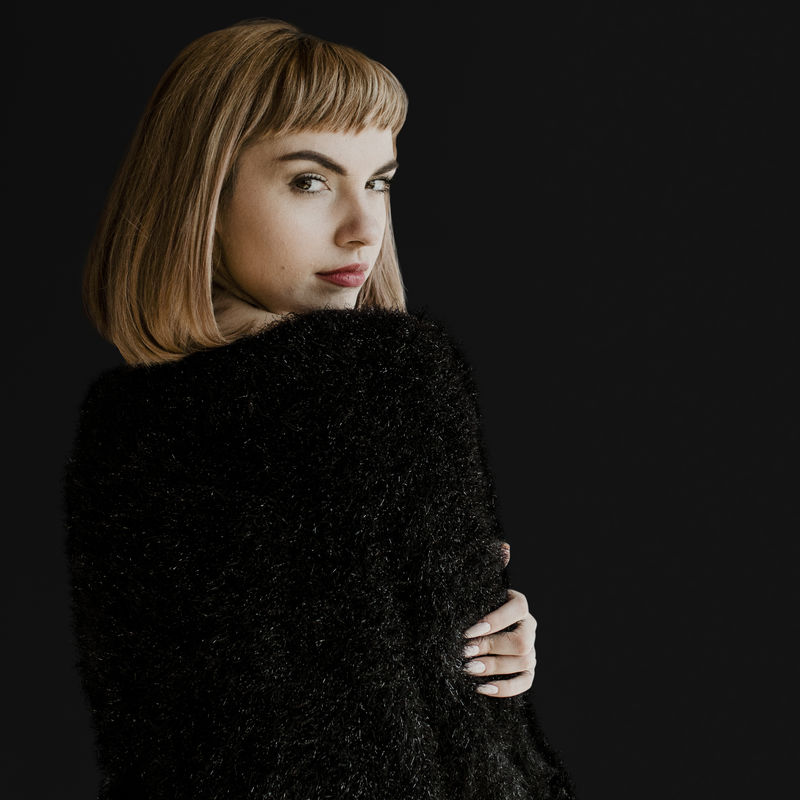 棕色头发的女人穿着一件黑色蓬松的毛衣回头看去