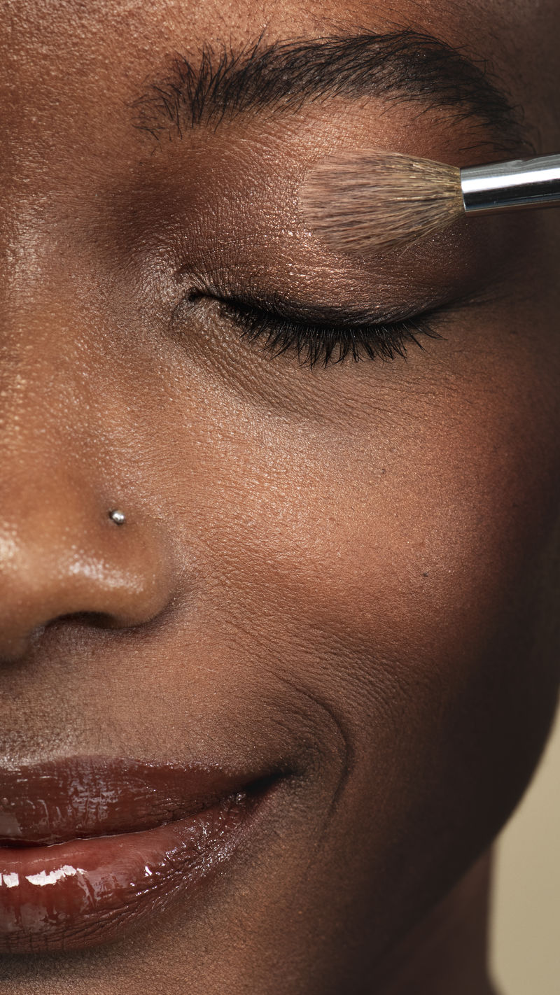 化妆师给黑人妇女涂眼影