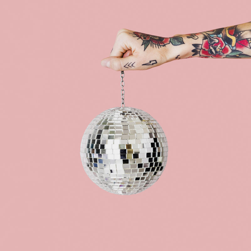 手拿着浅粉色背景的圣诞玻璃球