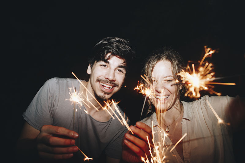 高加索男女情侣玩火花庆祝和节日派对概念