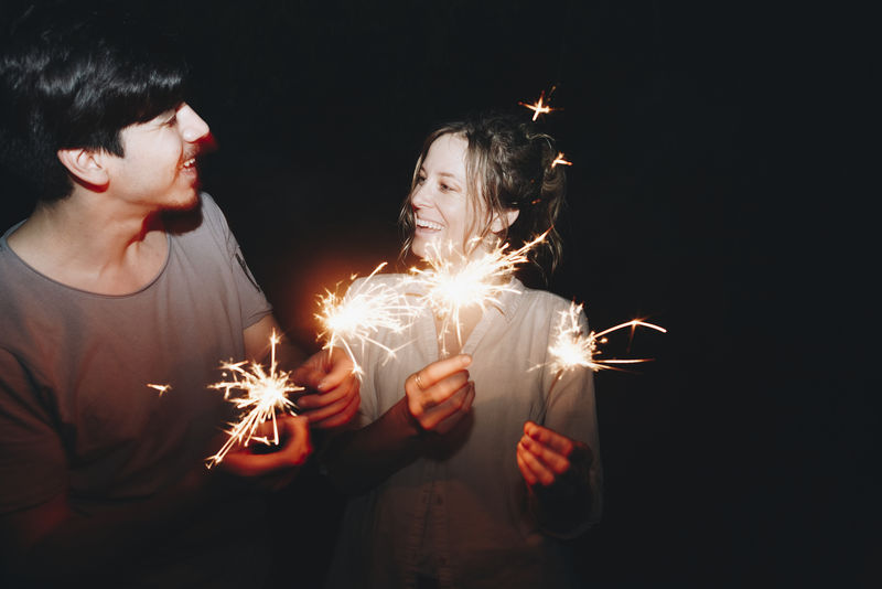 高加索男女情侣玩火花庆祝和节日派对概念
