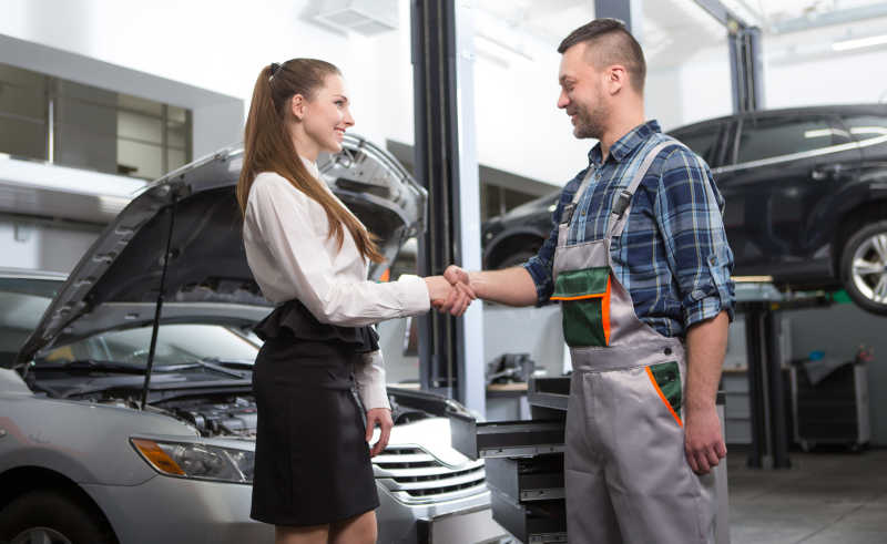 汽车车间修理人员和女士握手