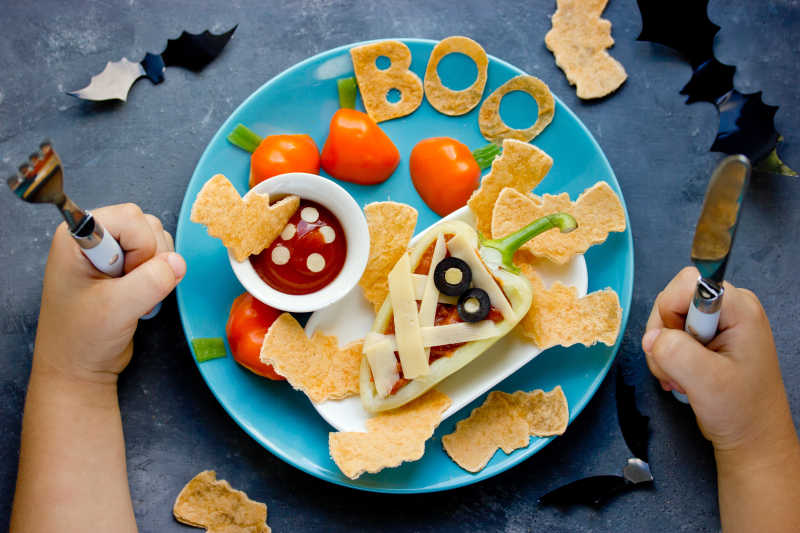 儿童吃万圣节风格的素食晚餐或午餐