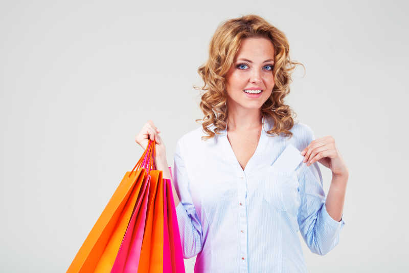 拎着购物袋从口袋拿出信用卡的女人